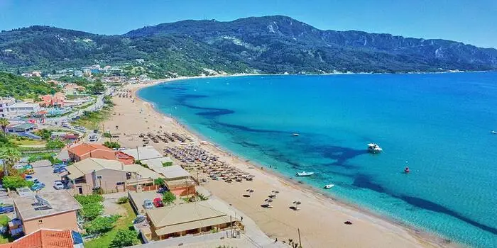 Agios Georgios Beach in Greece with clear blue water and sandy shoreline