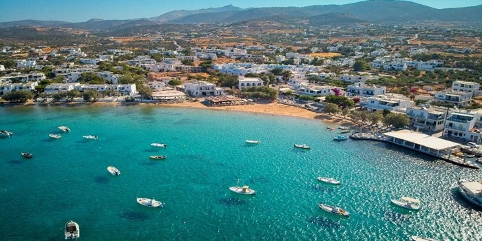 Aliki Beach in Paros, Greece with calm sandy shore, turquoise Aegean waters, and traditional village houses