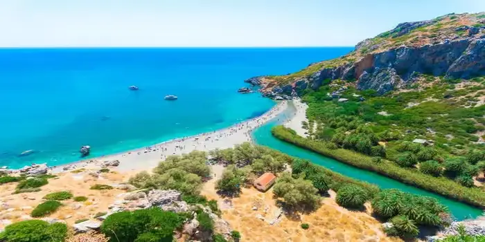 Damnoni Beach in Crete, Greece with turquoise water, sandy shore, and mountains in the background
