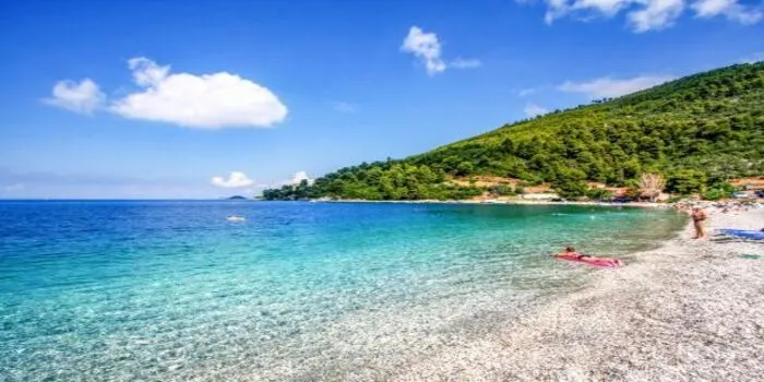 Panormos Beach in Crete, Greece with golden sand, turquoise water, and mountains in the background