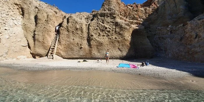 Tsigrado Beach in Milos, Greece with turquoise waters, white sand, and cliff access